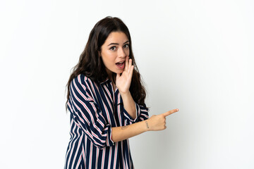 Fototapeta premium Young caucasian woman over isolated background pointing to the side to present a product and whispering something