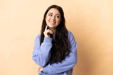 Young caucasian woman over isolated background thinking an idea while looking up