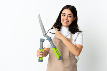 Young caucasian woman holding a plant isolated on white background pointing to the side to present...
