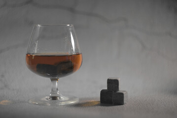 transparent whiskey on a gray background. whiskey stones in a glass