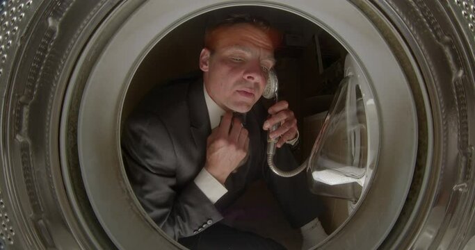 Crazy man imitates talking on the phone using a shower faucet, humorous psychotic condition with hallucinations like delirium tremens. Absurd situation laughably foolish. Funny portrait of businessman