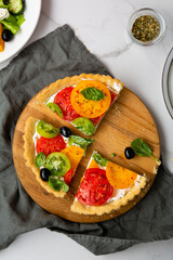 Overhead view of sliced  tomato cheese quiche on light surface