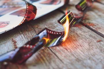 The burnt film lies on a wooden table. Vintage things that have long been out of use. Throw away old things to make room for new things. Film cameras were once fashionable.
