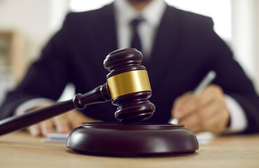 Close up shot of dark brown wooden gavel on sound block placed on desk in lawyer's office. Closeup...
