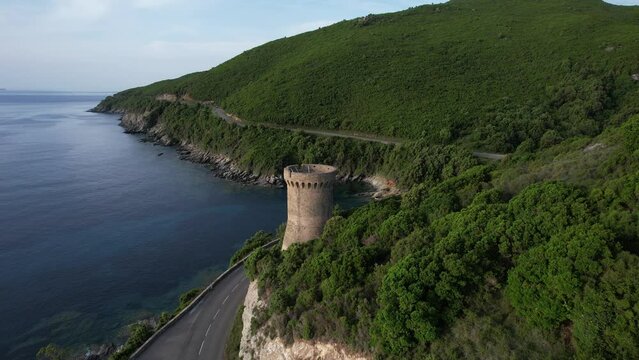 voiture roulant tranquillement sur une route du Cap Corse au dessus de la M&eacute;diterran&eacute;e et une tour g&eacute;noise - Corse