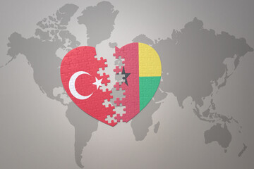 puzzle heart with the national flag of turkey and guinea bissau on a world map background. Concept.