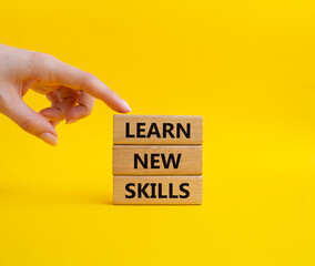 Learn new skills symbol. Concept words 'Learn new skills' on wooden blocks. Beautiful yellow background. Businessman hand. Business and Learn new skills concept. Copy space.