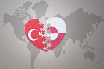 puzzle heart with the national flag of turkey and greenland on a world map background. Concept.