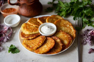 Snack for the whole family: potato pancakes on a beautiful plate with fresh herbs on a gray background. Belarusian draniki for lunch. Close-up