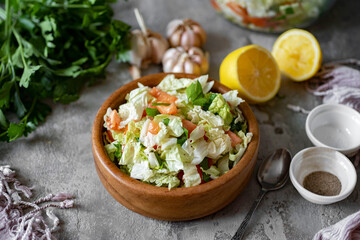 Vegetarian lunch. Salad of fresh vegetables: cabbage, tomatoes, onions, parsley, cucumbers in a beautiful wooden bowl on a gray background. Vegetable salad for breakfast. Close-up