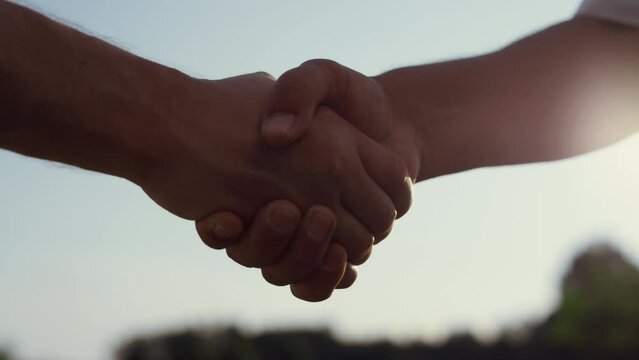 Caucasian people shaking hands outdoors. Two business partners on summer nature.