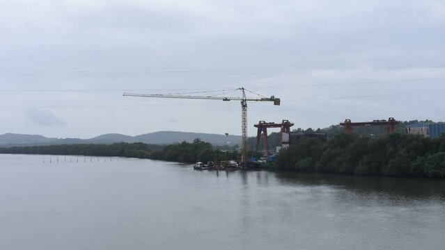 HD scenery of the Zuari river flowing through Borim village in Goa India with a view of a Chowgule Shipyard shipbuilding company and Borim Bridge