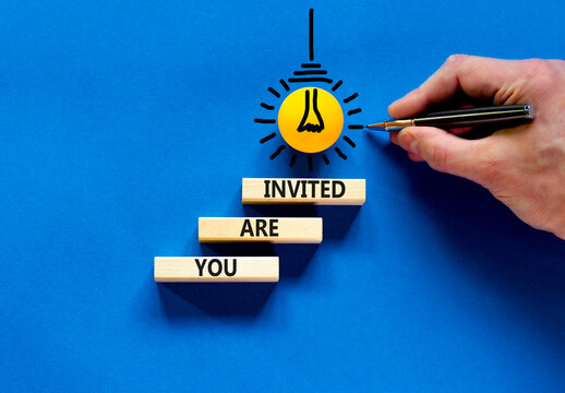 You are invited symbol. Concept words You are invited on wooden blocks. Businessman hand. Light bulb icon. Beautiful blue table blue background. Business and you are invited concept. Copy space.