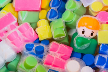 Washing of children toys, plastic building blocks with figurines. A smiling little fellow and colorful cubes float in the foaming water. The concept of hygiene, cleanliness. Safety and disinfection