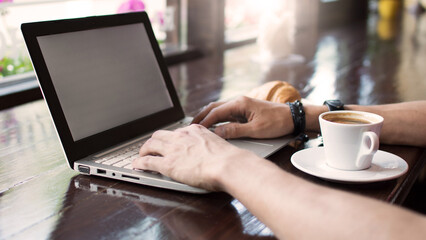 Young man freelancer working from a cafe with a laptop, hipster guy using modern laptop computer while working in a vintage loft, close-up of male hands.