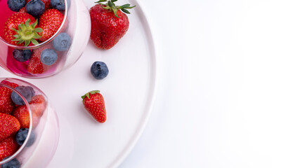 Fruit jelly dessert or panna cotta with fresh strawberries and blueberries, top view, banner, copy space, menu, template for texts on white background
