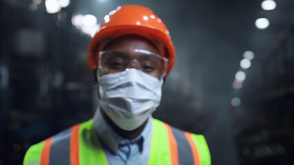 Masked supervisor looking camera at huge energy manufacturing special factory.