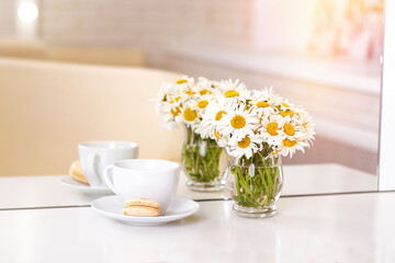 Client's place in hairdressing and beauty salon with cup of tea, macaroon and chamomiles in vase
