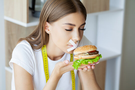 Portrait woman wants to eat a Burger but stuck skochem mouth