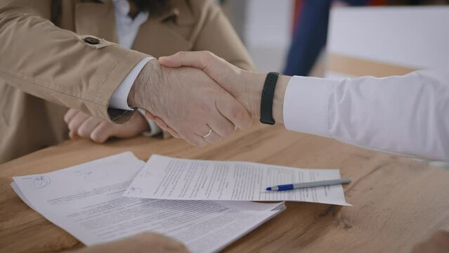 A man signs a contract to purchase a new car. Close-up of a handshake.