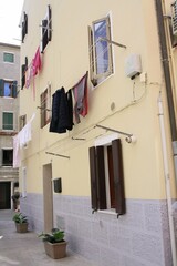 Ropa extendida en las cuerdas de fachada de casa antigua en pueblo pesquero italiano