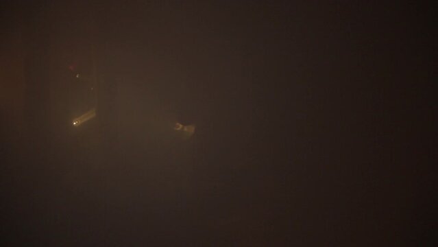 Rescuers are looking for people in a dark tunnel in dense smoke with flashlights. Image without sharpness.