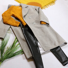 Stylish women's outfit knitted mustard sweater, gray autumn coat, leather pants mustard beret and yellow scarf on a white background.