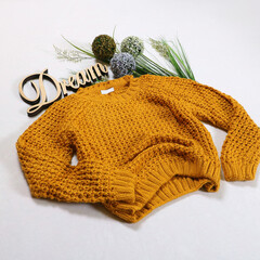 a knitted yellow sweater on a white background with a wooden inscription Dream. Stylish women's outfit
