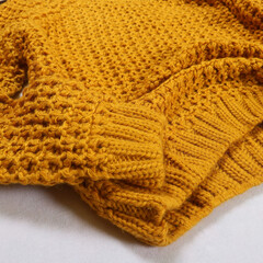 close-up of a knitted yellow sweater on a white background. Stylish women's outfit