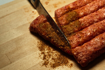 Minced meat with seasoning on a wooden board, a knife cuts minced meat, photo indoors