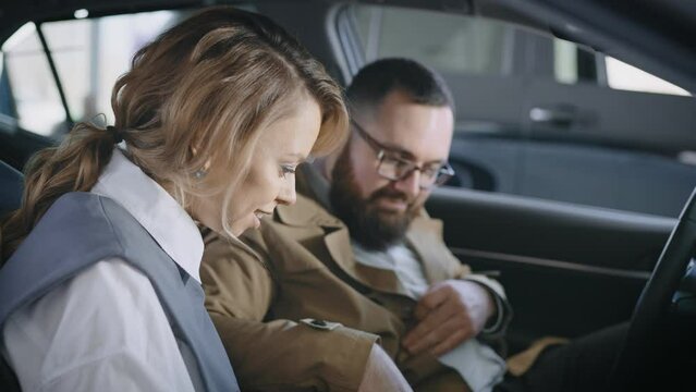A married couple in the salon of a new car. Husband and wife are discussing buying a car from a car dealership.