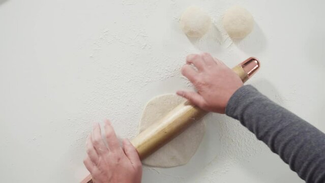 Flat lay. Rolling bread dough with a french rolling pin to make homemade flatbread.