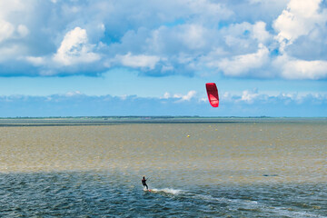 Kitesurfer in stormy weather on the Wadden Sea in the north of the Netherlands. On de horizon the...
