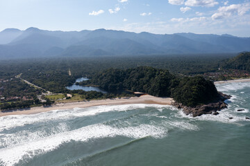 Vista aérea de uma linda praia do litoral paulista com areia clara, mar, costa e um rio