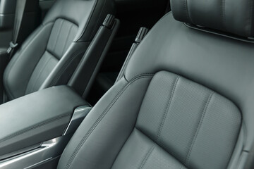 Close-up of a black genuine leather driver's seat with a folding armrest. Place for the logo. Beautiful leather car interior design. Luxury leather seats in the car.