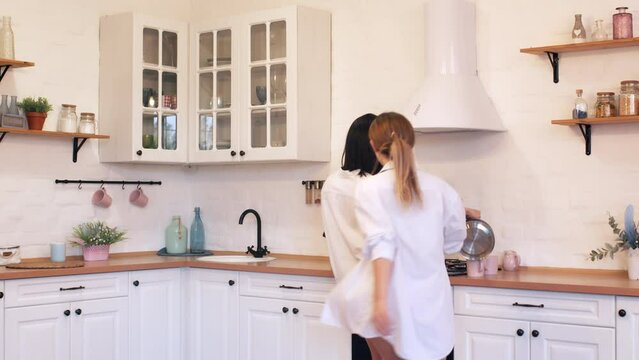 Young happy couple of lesbians have fun dancing at home in the kitchen, valentines day concept.