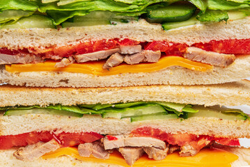 Sandwich with ham and vegetables. Sandwich background, Layers of a sandwich with cheese, lettuce, meat, tomatoes and cucumbers.
