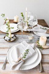 Rustic zero waste wedding decor with natural elements. Wooden table, candles, linen napkins, branches with green leaves. Eco-friendly decoration for the special dinner. Romantic and cozy place