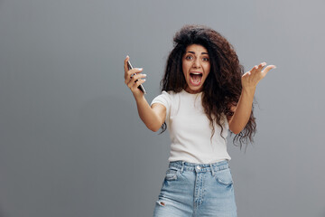 Lucky Win. Joyful Brunette Woman Celebrating Success With Smartphone, Happy Latin Lady Won Online Lottery, Holding Cellphone And Raising Hands Up, Posing On Gray Studio Background, Free Space