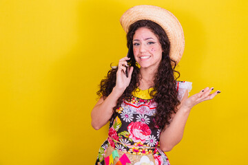 Beautiful woman dressed in typical clothes for a Festa Junina. talking by audio call on cell phone.