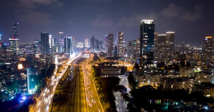 Night aerial hyperlapse of tel aviv skyline with urban skyscrapers, beautiful moving clouds, and cars on highway Israel