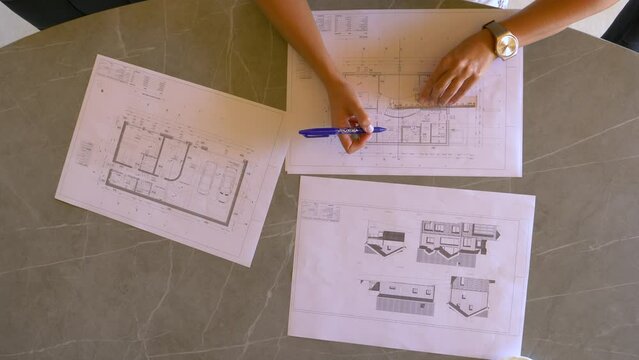 TOP DOWN: Female feng shui expert drawing energy lines on house building plan. Young woman analysing energy flow distribution and making feng shui plan for home residence and balanced interior design.