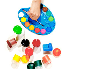 Jars with gouache multicolored paint, palette, brush. Top view.Flat lay