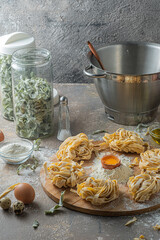 Freshly made tagliatelle pasta with eggs and flour on wooden board