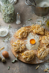 Freshly made tagliatelle pasta with eggs and flour on wooden board