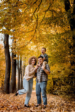 Portrait of happy young family on the background of autumn park. Mom, dad and son are smiling. Family autumn photo shoot