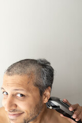 Obraz premium Handsome gray-haired man is cutting hair himself.