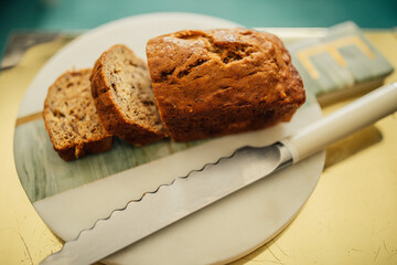 high angle view of sliced mini loaf of banana almond bread on marble, gold with serrated knife - Powered by Adobe