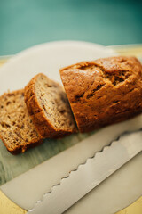 high angle view of sliced mini loaf of banana almond bread on marble, gold with serrated knife
