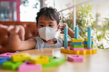 Asian Girl With healthy Face Mask Concentrated Plying color Wooden blocks.